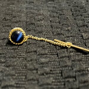 Men’s gold tie clip with blue cats eye gemstone.